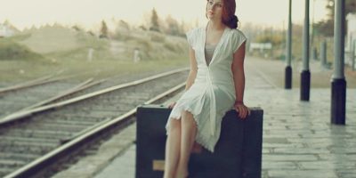 Mujer sentada sobre una maleta en una estación de tren